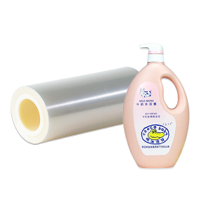 Various bottles of cleaning products, including laundry detergent and surface cleaners, alongside rolls of white PE label film.