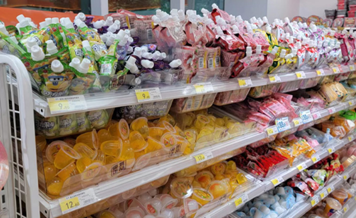 Neatly arranged beverage shelves in a supermarket, displaying a variety of packaged foods and clear price tags