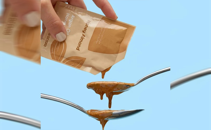 Honey almond paste packaging and pouring process on fresh sky blue background, showing details of thick brown-yellow liquid flowing along the spoon